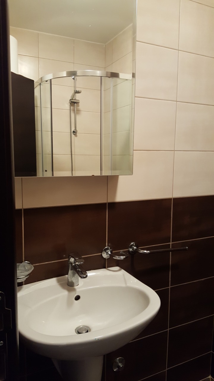 Budva, Karadağ’daki bir dairede beyaz lavabolu ve duş kabinli banyo. Modern fayans kaplaması.