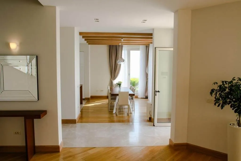 Jasny salon z jadalnią i drewnianymi belkami w willi w Blizikuće, Czarnogóra. Nowoczesne wnętrze.