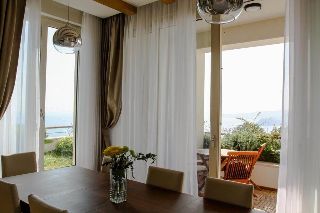 Dnevna soba sa trpezarijskim delom i panoramskim pogledom na more u vili, Blizikuće, Crna Gora. Moderan enterijer sa terasom.