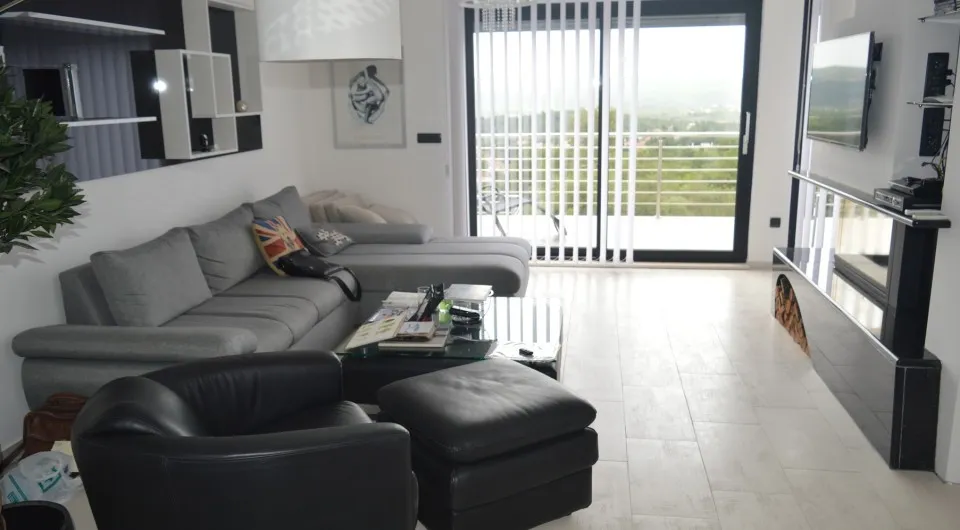 Modernes Wohnzimmer mit Kamin und Panoramablick auf die Terrasse in einer Villa in Tivat, Montenegro. Innenraum mit Ledermöbeln.