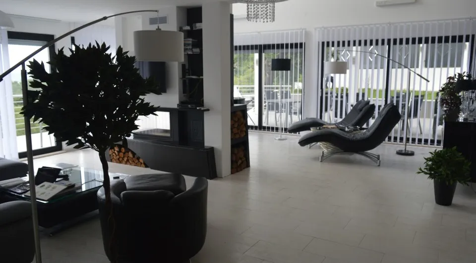 Modernes Wohnzimmer in einer Villa in Tivat, Montenegro: Ledermöbel, Kamin mit Brennholz und Panoramafenster mit Terrasse.