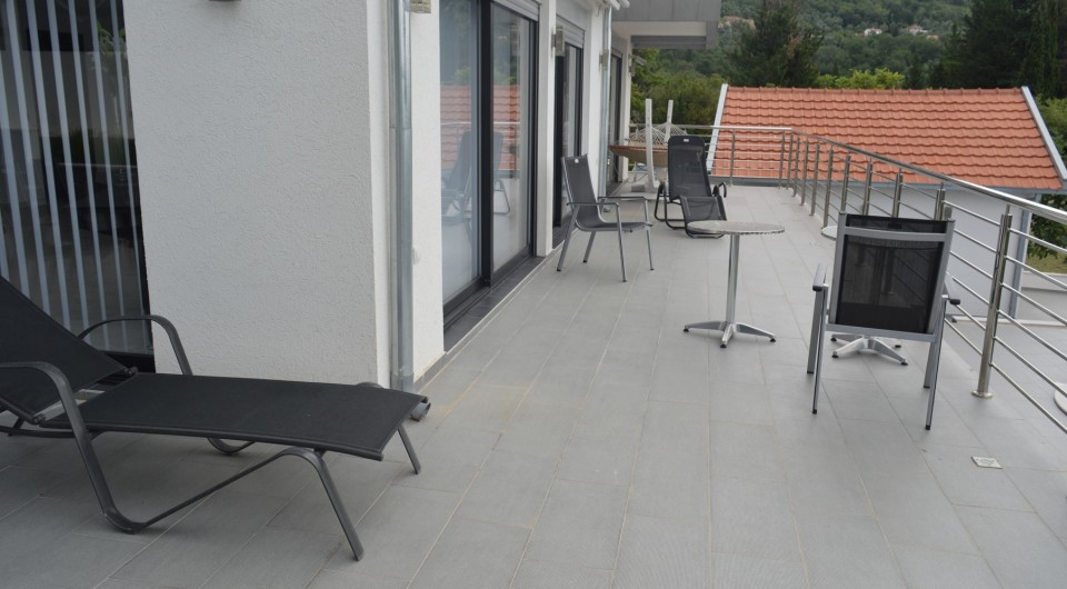 Karadağ, Tivat'ta, bahçe mobilyaları, şezlonglar ve yeşil tepelerin panoramik manzarasına sahip geniş villa terası.
