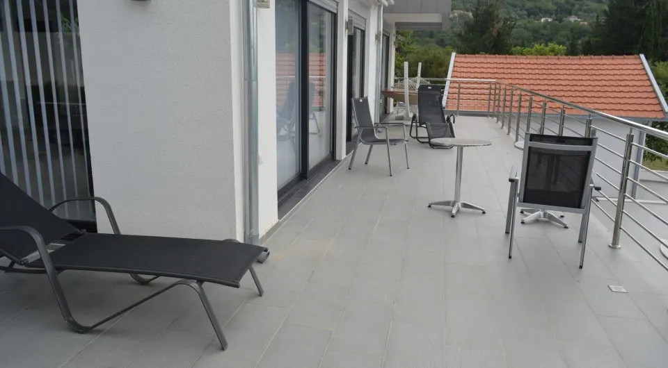 Geräumige Terrasse der Villa in Tivat, Montenegro, mit Gartenmöbeln, Liegestühlen und Panoramablick auf die grünen Hügel.