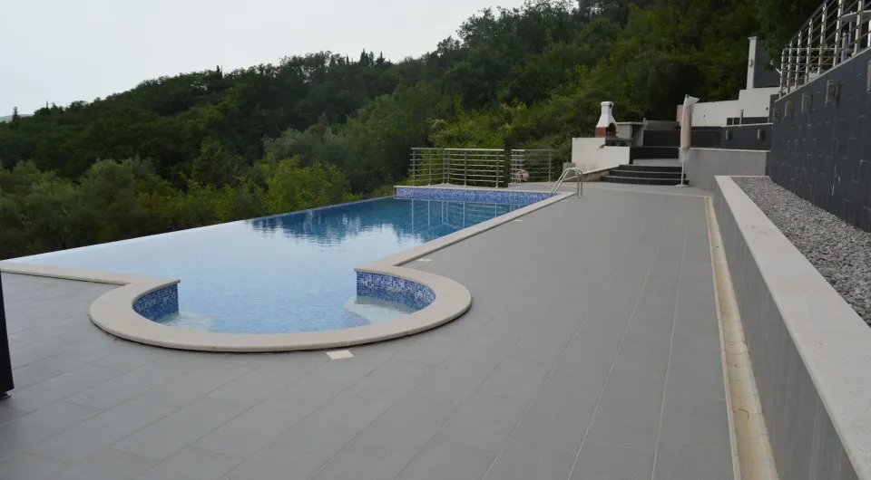 Offener Pool mit Terrasse und Grillbereich in einer Villa in Tivat, Montenegro, vor einer malerischen Waldlandschaft.