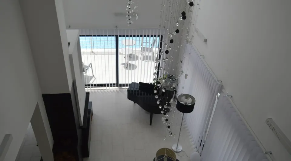 Wohnzimmer mit Flügel und Panoramafenstern in einer Villa in Tivat, Montenegro: modernes Interieur mit großem Kronleuchter.