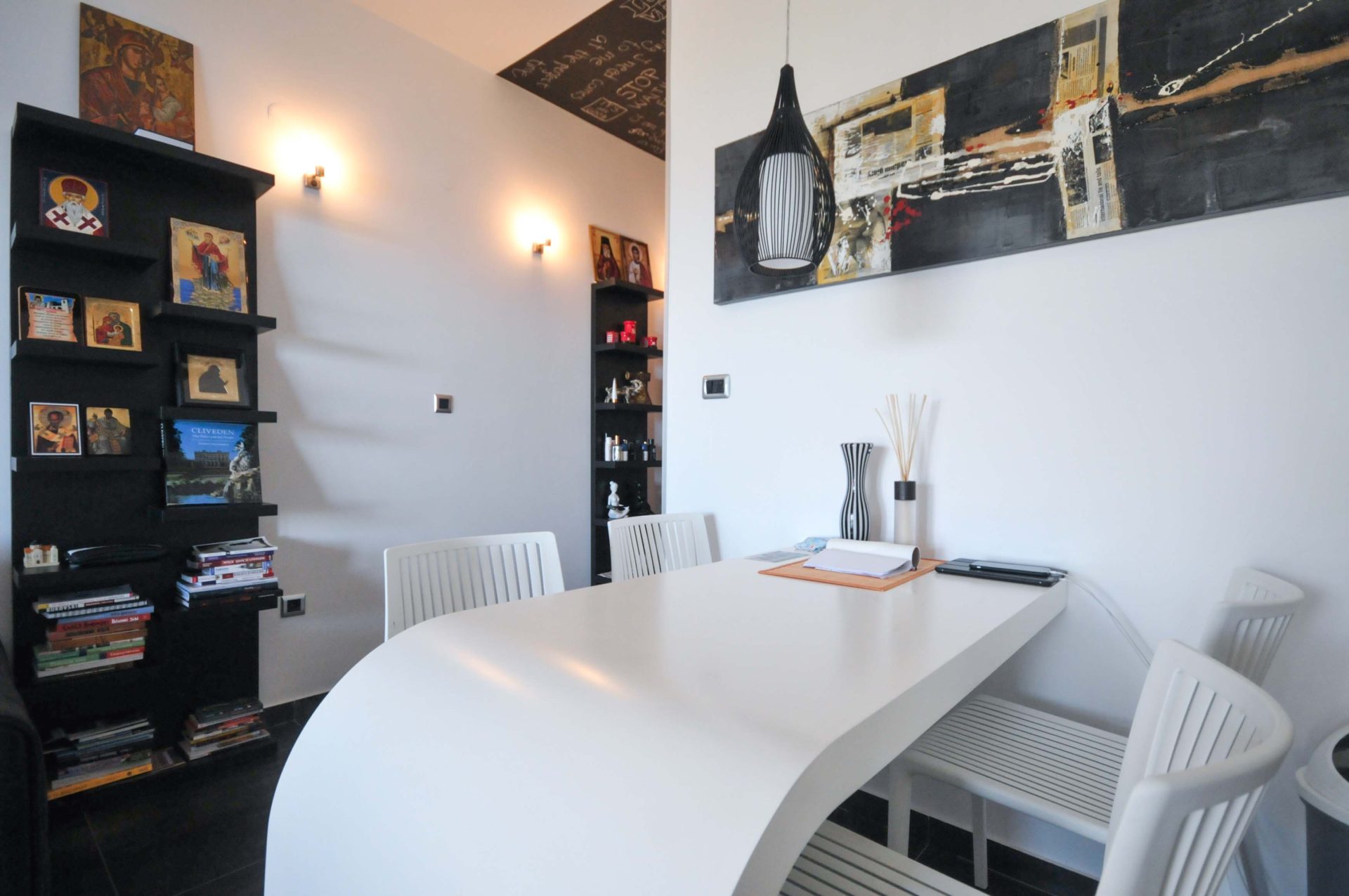Modernes Wohnzimmer in einer Wohnung in Pržno, Montenegro: weißer Esstisch, Designer-Dekor und schwarze Regale.