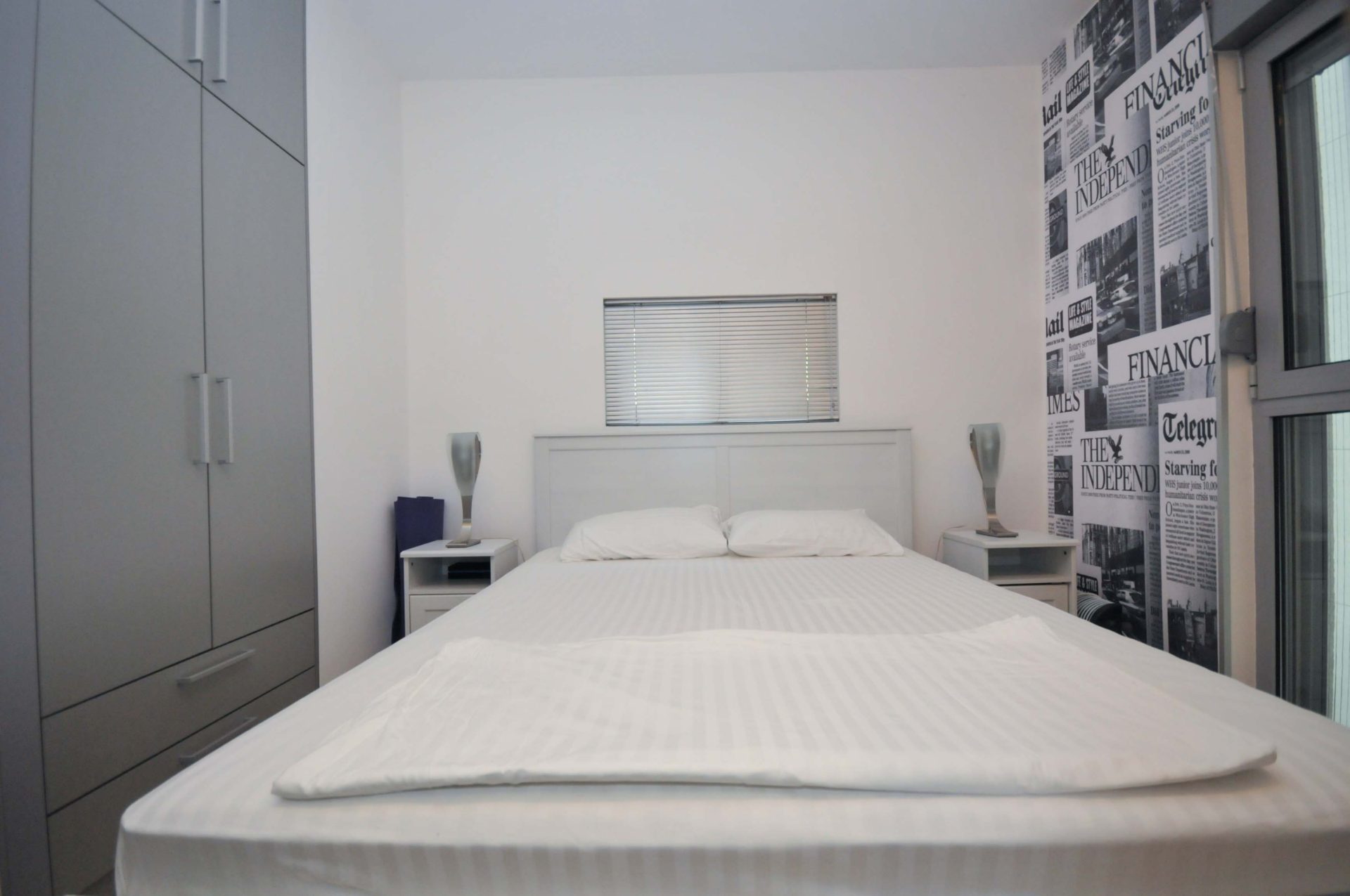 Modernes Schlafzimmer in einer Wohnung in Pržno, Montenegro: Doppelbett, grauer Kleiderschrank und Akzentwand mit Print.