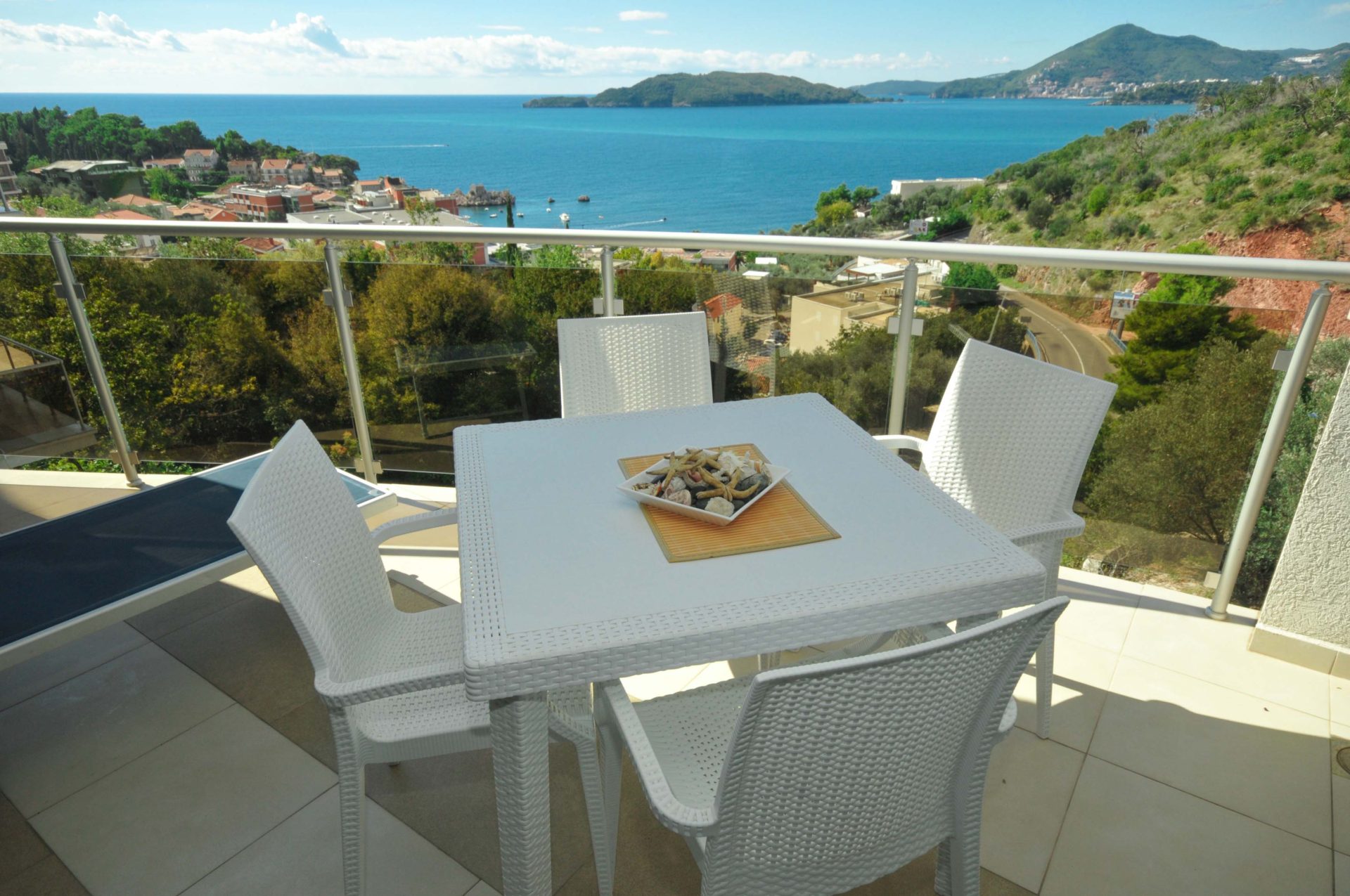 Terrasse mit weißen Möbeln und Panoramablick auf das Meer in einer Wohnung in Pržno, Montenegro.