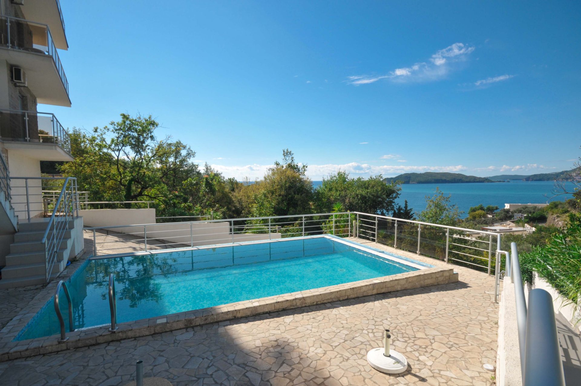 Offener Pool auf der Terrasse mit Panoramablick auf das Meer in Pržno, Montenegro. Steinverkleidung und moderne Umzäunung.