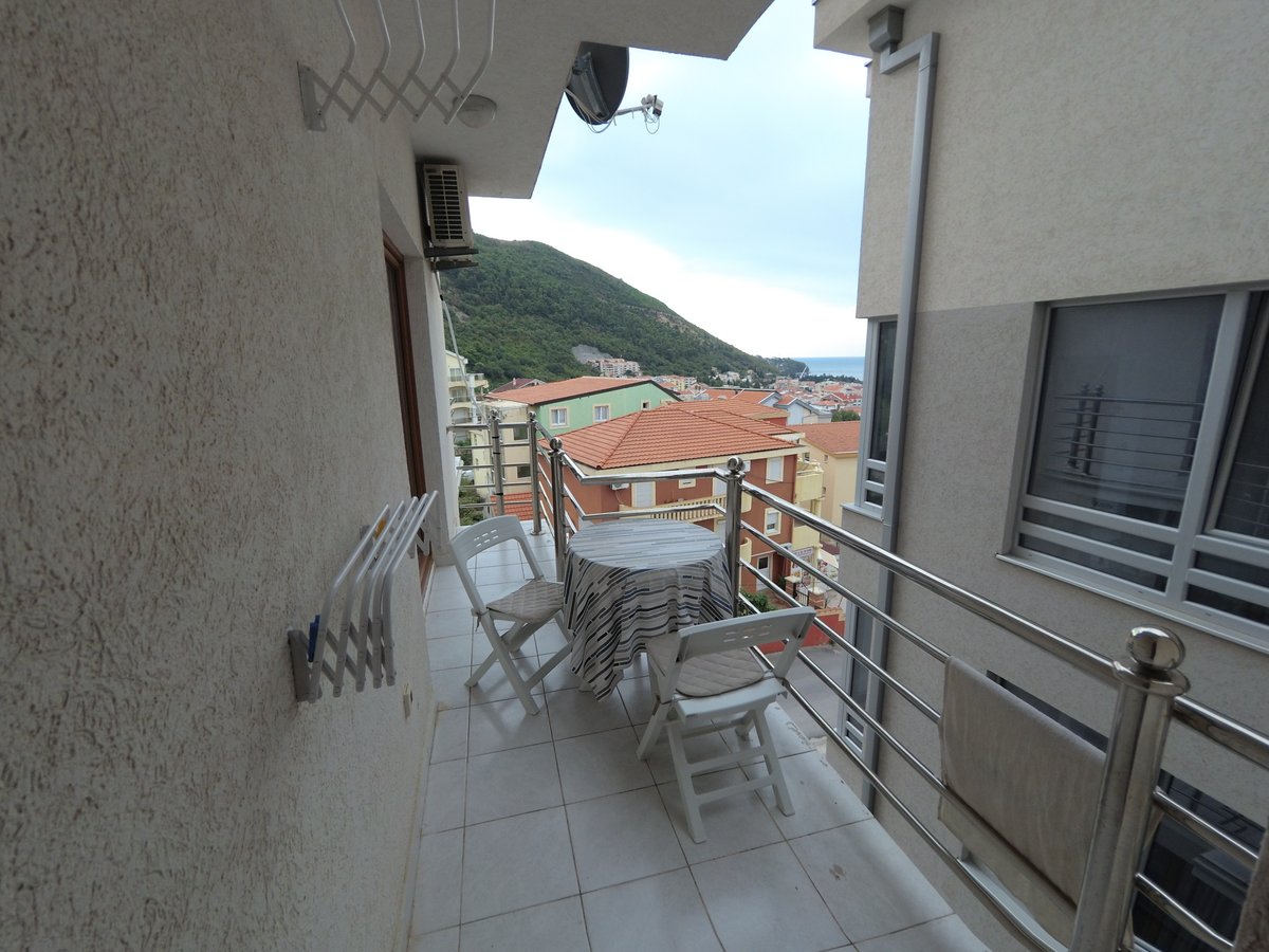 Balkon sa nameštajem i pogledom na planine i more u stanu u Budvi, Crna Gora. Svetla završna obrada i pločice na podu.