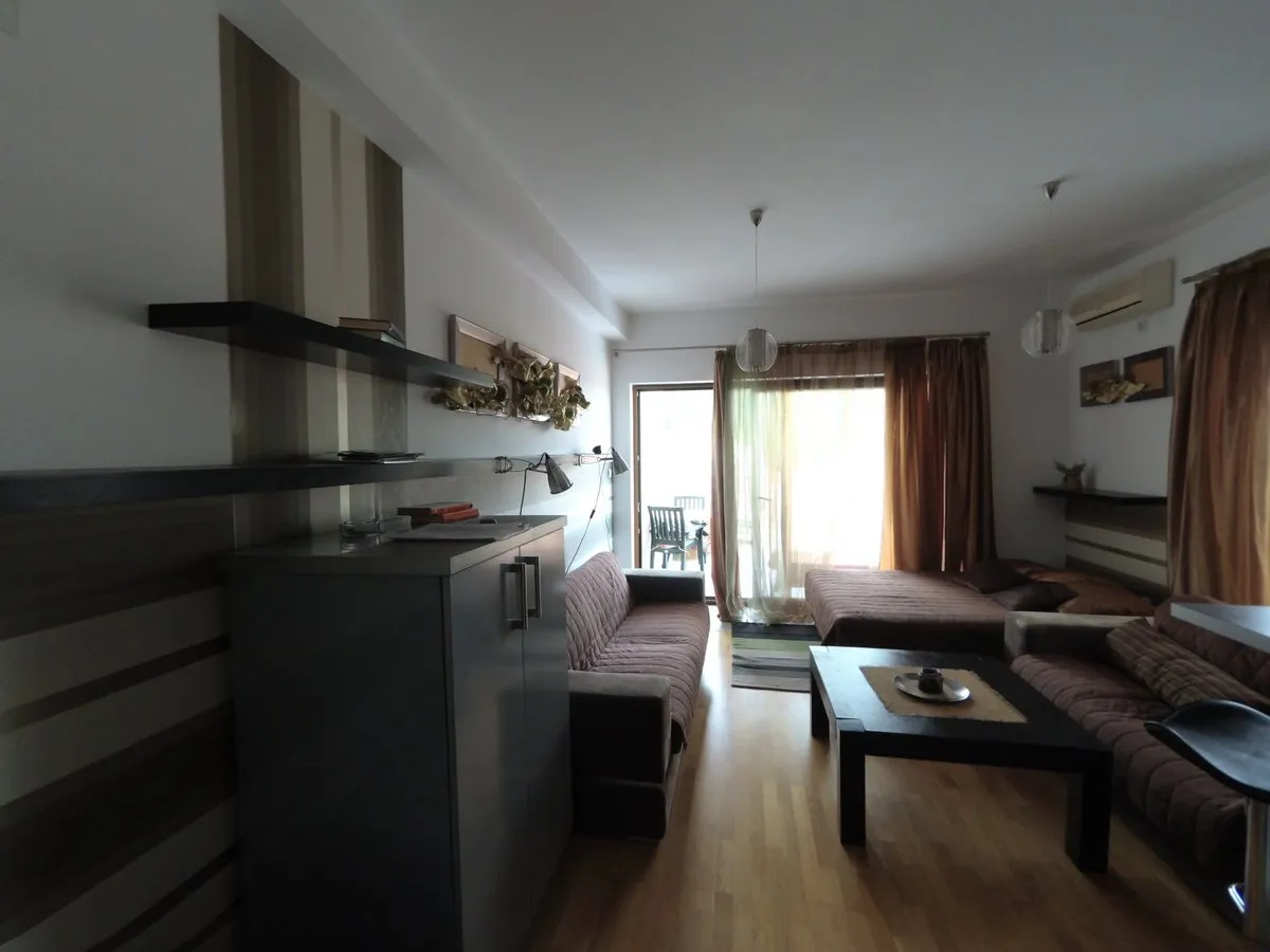 Gemütliches Wohnzimmer mit Möbeln und Zugang zur Terrasse in einer Wohnung in Budva, Montenegro. Modernes Interieur mit Parkettboden.