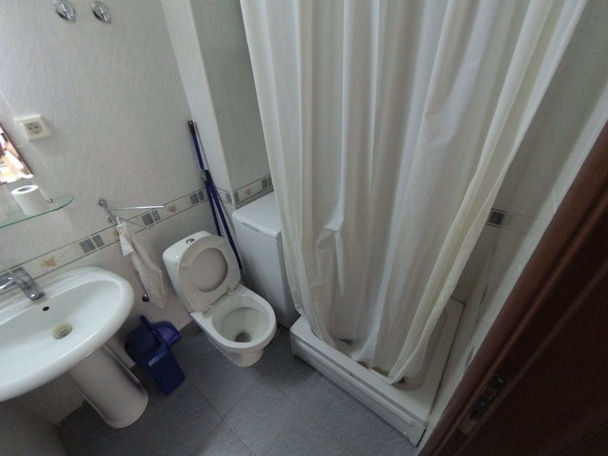 Kupatilo u stanu u Budvi, Crna Gora: svetle pločice, sanitarije, tuš kabina i veš mašina.