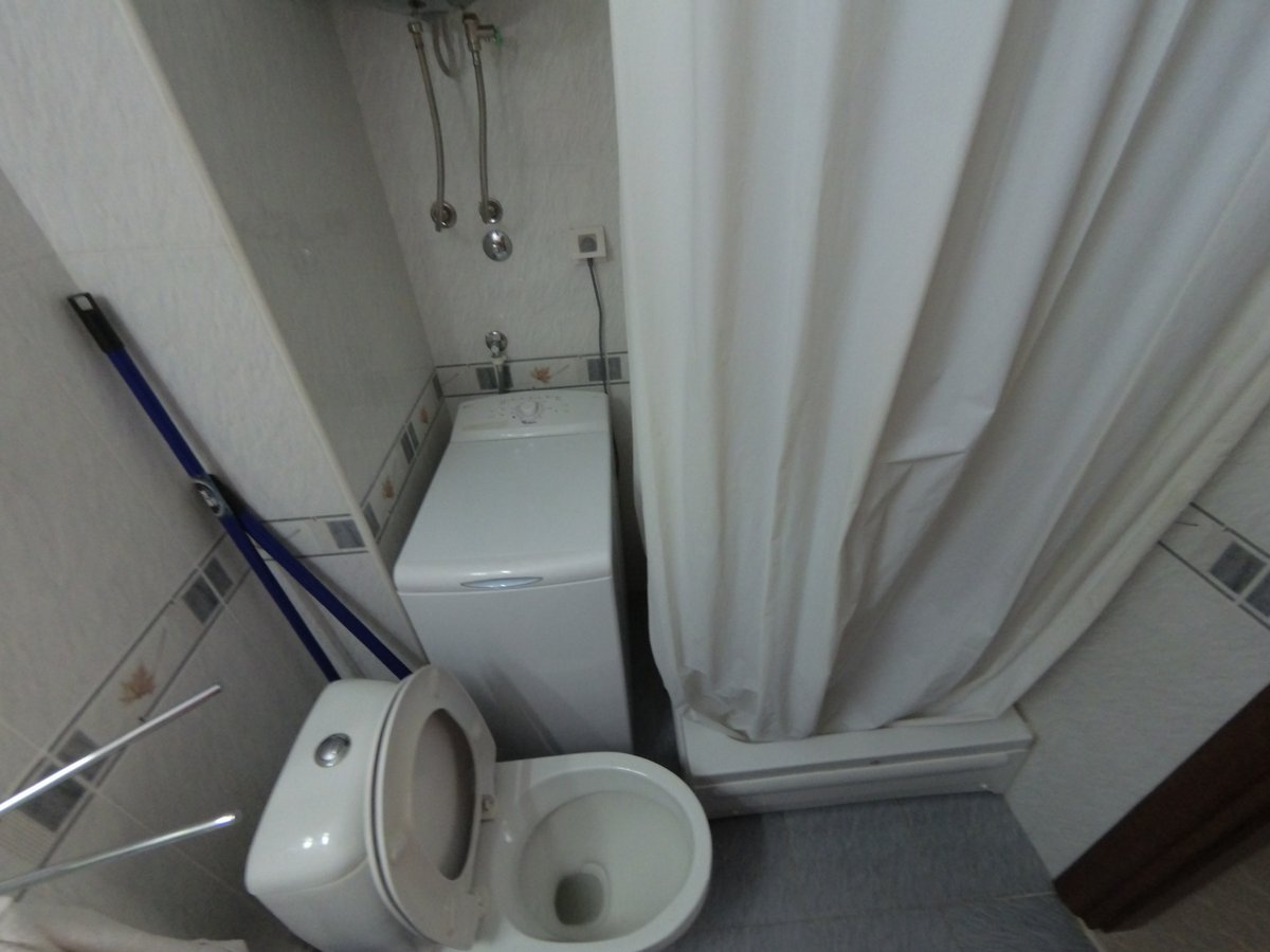 Kupatilo u stanu u Budvi, Crna Gora: kompaktan sanitarni čvor sa tuš kabinom, toaletom i veš mašinom.