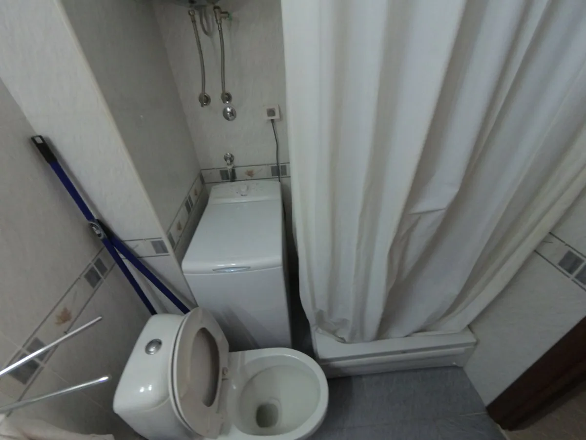 Badezimmer in einer Wohnung in Budva, Montenegro: kompaktes Bad mit Duschkabine, Toilette und Waschmaschine.
