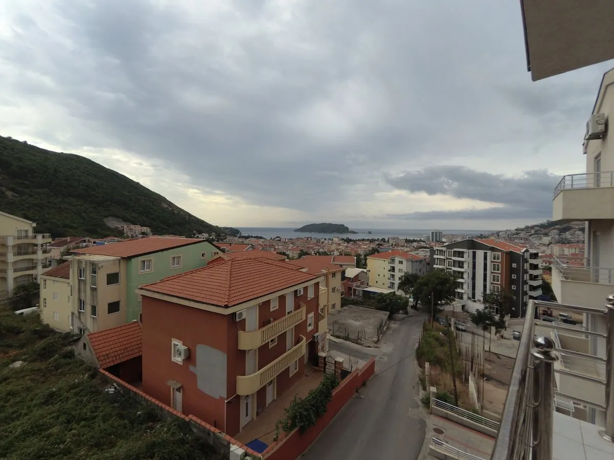 Blick vom Balkon der Wohnung in Budva, Montenegro: Panorama der Stadt, rote Ziegeldächer, Berge und die Meeresbucht.