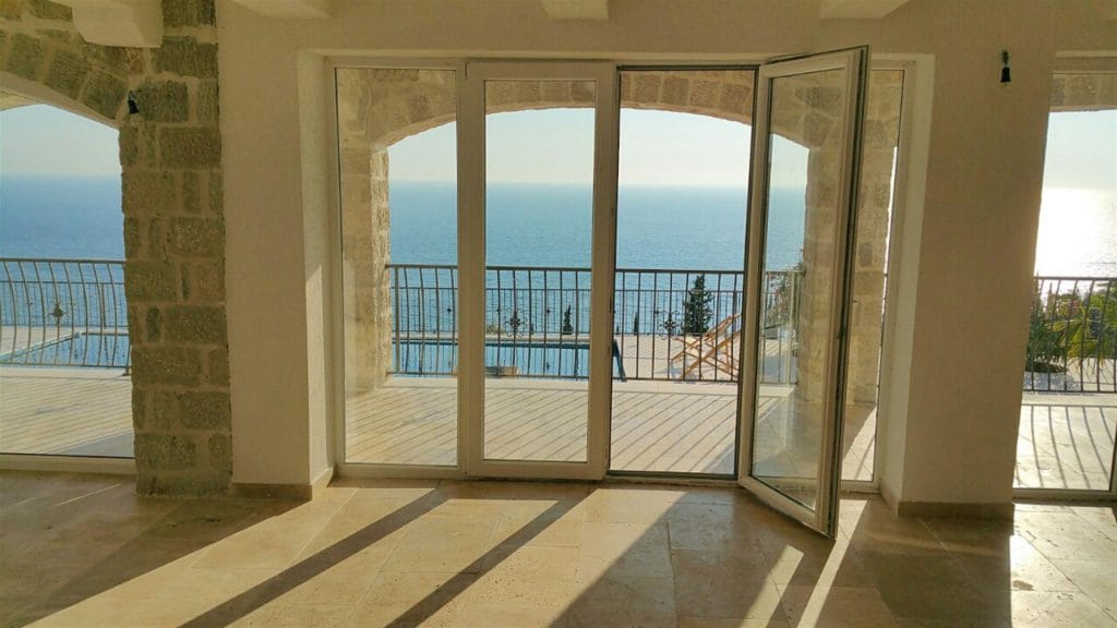 Karadağ, Drobni Pijesak’taki villanın oturma odası: panoramik deniz manzarası, havuzlu teras ve kemerlerde taş kaplama.