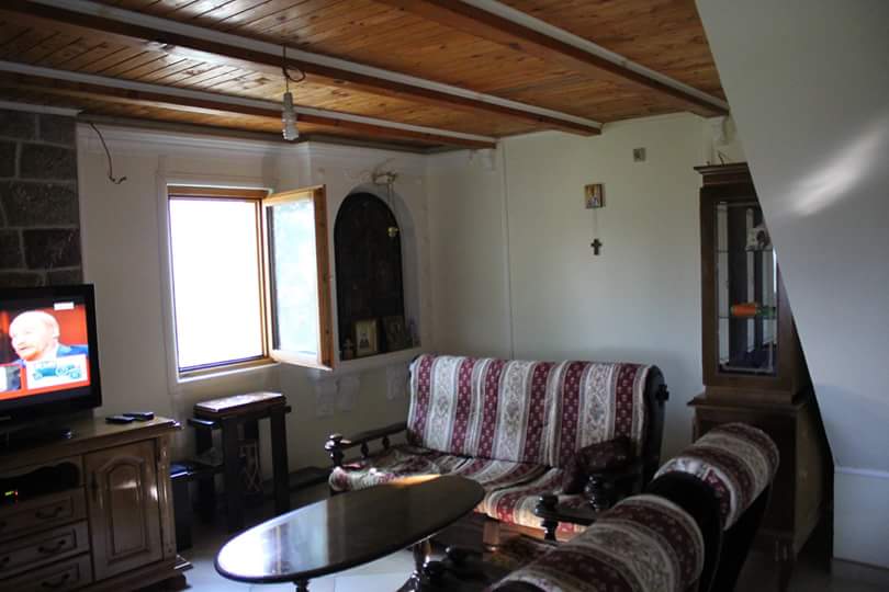 Salon dans une maison à Sutomore, Monténégro : plafond en bois, mobilier rembourré, vitrine et télévision dans l’intérieur.