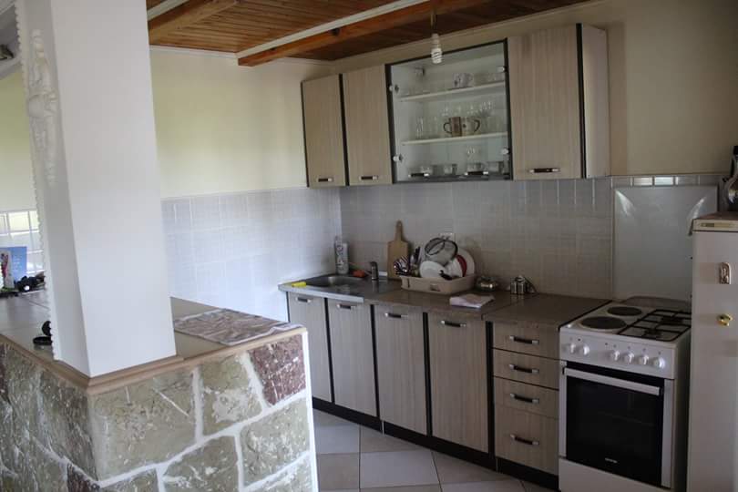 Cuisine dans une maison à Sutomore, Monténégro : mobilier clair, cuisinière, finition en pierre du comptoir du bar et plafond en bois.