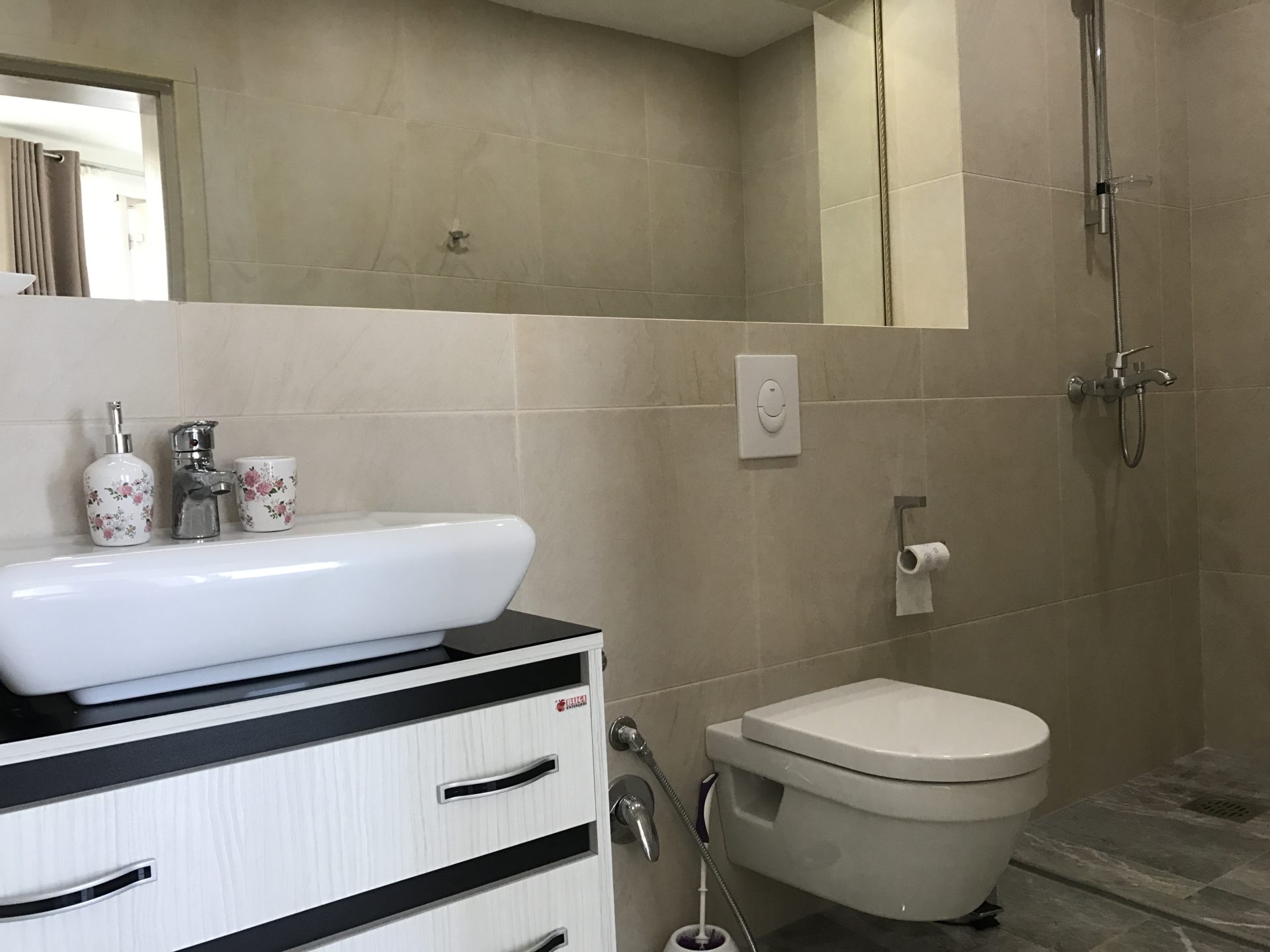 Modernes Badezimmer mit Duschkabine in einer Villa in Uteha, Montenegro: weiße Sanitärkeramik und beige Fliesen.