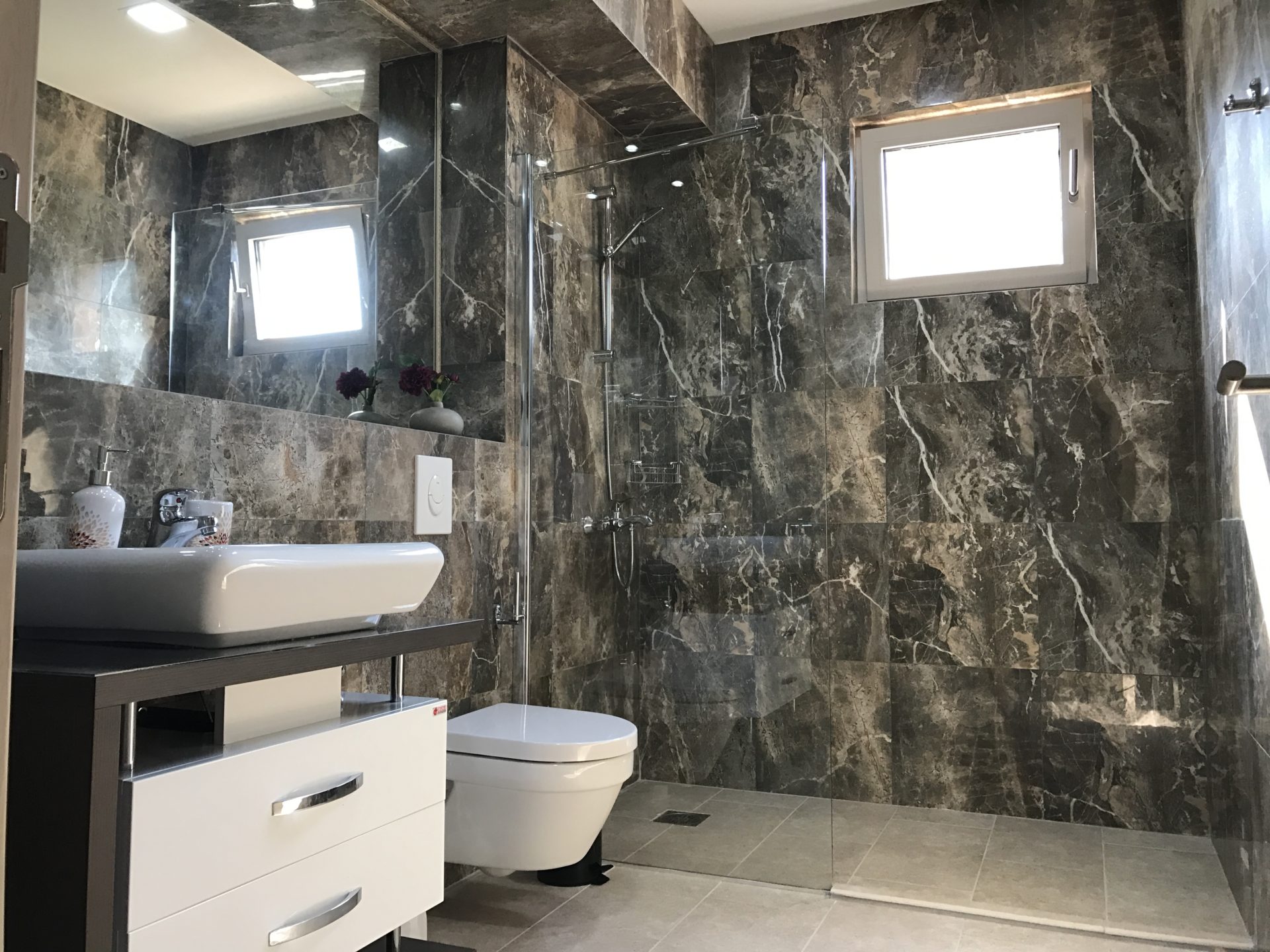 Modernes Badezimmer mit dunkler Marmorverkleidung und Duschkabine in einer Villa in Utjeha, Montenegro.