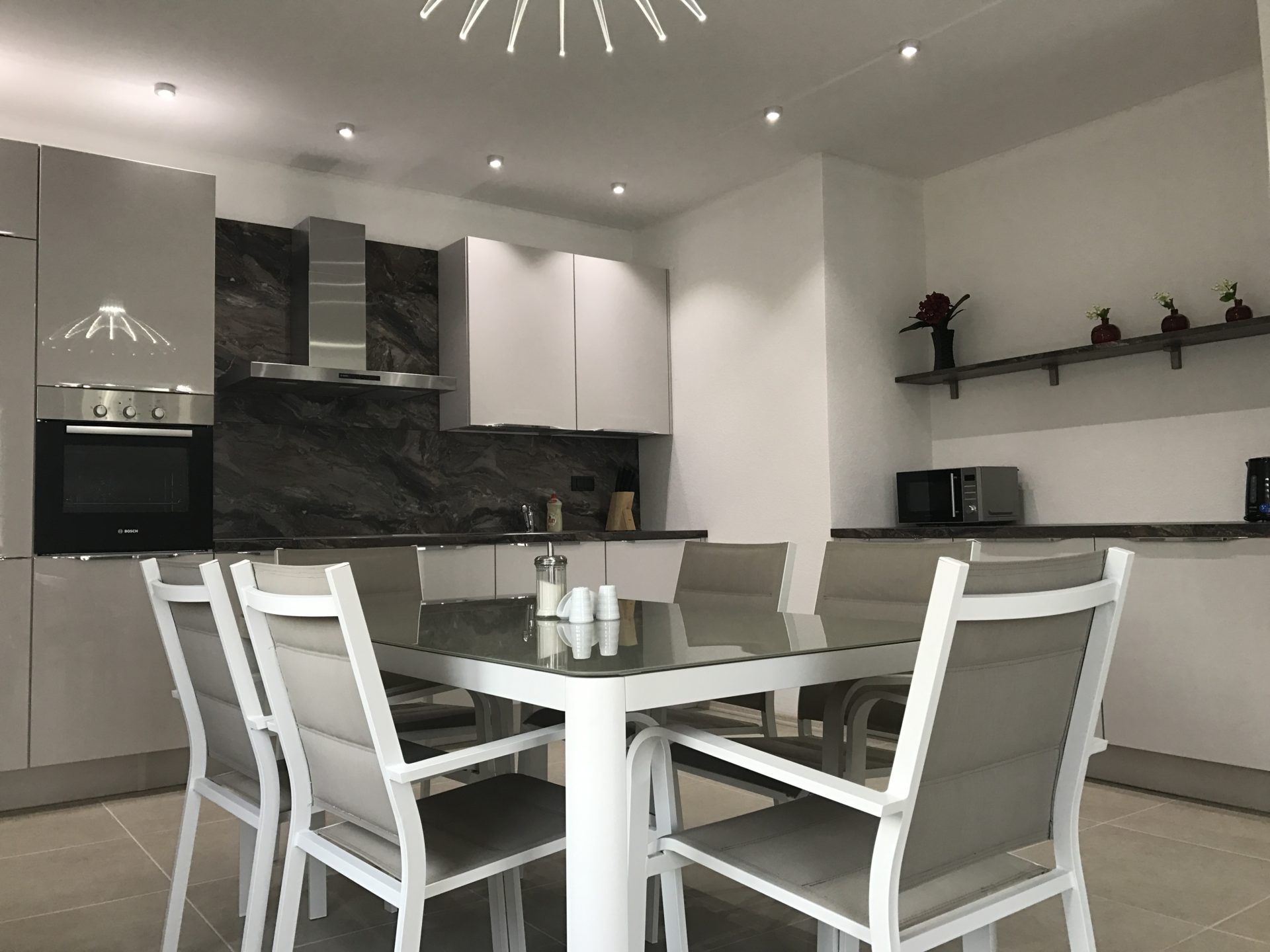 Moderne Küche mit Glastisch in einer Villa in Utjeha, Montenegro: stilvolles Interieur und Einbaugeräte.