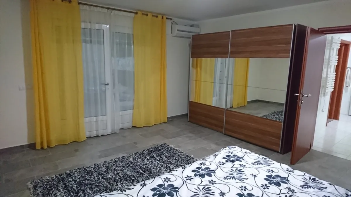 Bedroom in a villa in Utjeha, Montenegro: double bed, mirrored sliding wardrobe, yellow curtains, and access to the terrace.