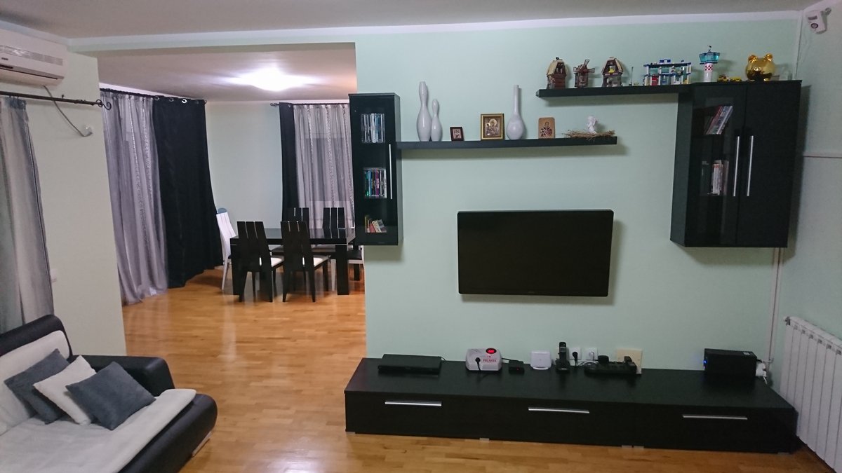 Wohnzimmer mit schwarzen Möbeln und Essbereich in einer Villa, Utjeha, Montenegro. Helle Wände, Parkett, TV-Bereich und Dekor.