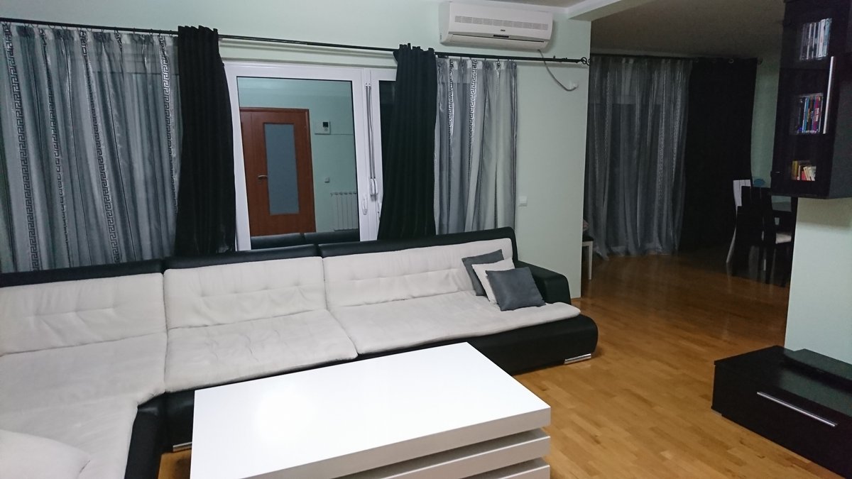 Wohnzimmer mit schwarz-weißem Sofa und Parkett in einer Villa in Utjeha, Montenegro. Innenraum mit Klimaanlage und Panoramafenstern.