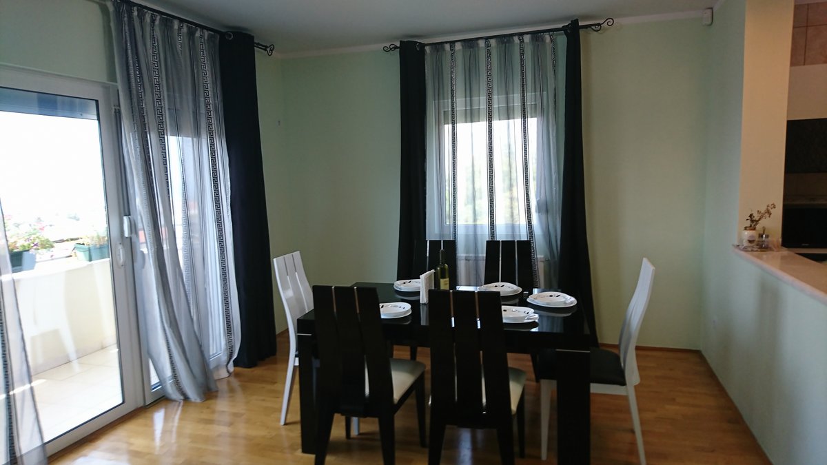 Wohnzimmer mit Essbereich in einer Villa in Uteha, Montenegro: schwarzer Tisch, kontrastierende Stühle und Zugang zur Terrasse.