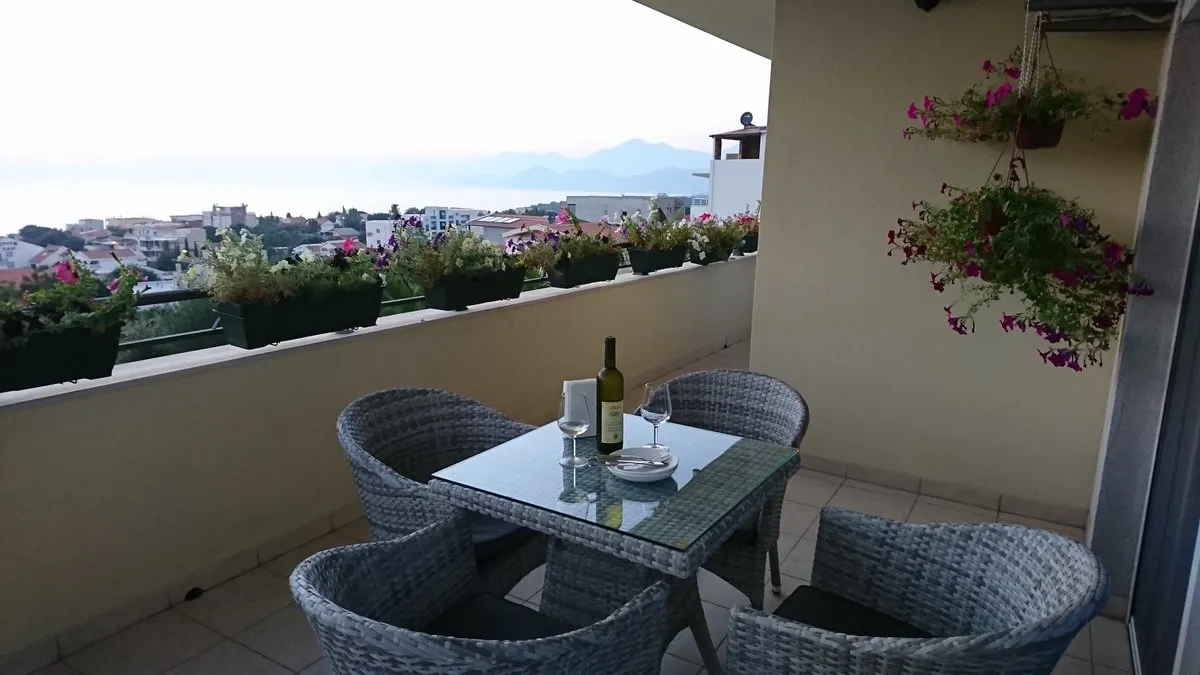 Terrace with wicker furniture and sea view in a villa in Utjeha, Montenegro: a cozy balcony with flowers and a dining area.