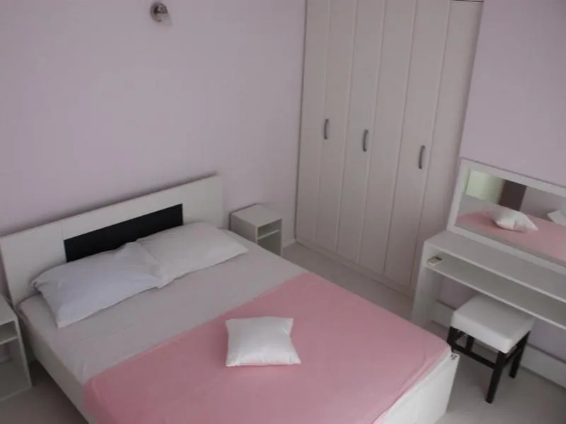 Svetla spavaća soba sa bračnim krevetom, ormarom i toaletnim stočićem u kući, grad Tivat, Crna Gora.