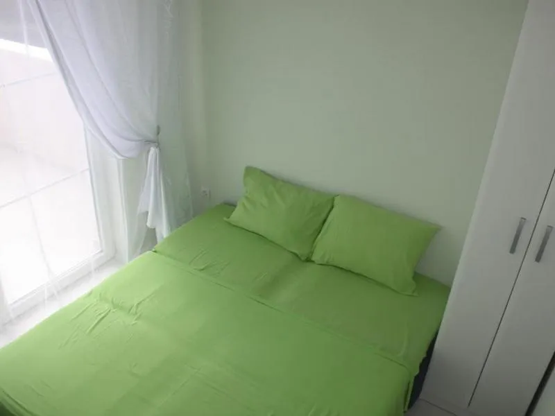 Svetla spavaća soba sa bračnim krevetom i belim ormarom u kući, grad Tivat, Crna Gora. Pogled na balkon.