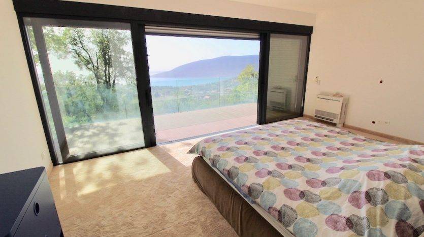 Karadağ, Herceg Novi’deki villada yatak odası: deniz manzaralı panoramik pencere, teras ve modern iç mekan.