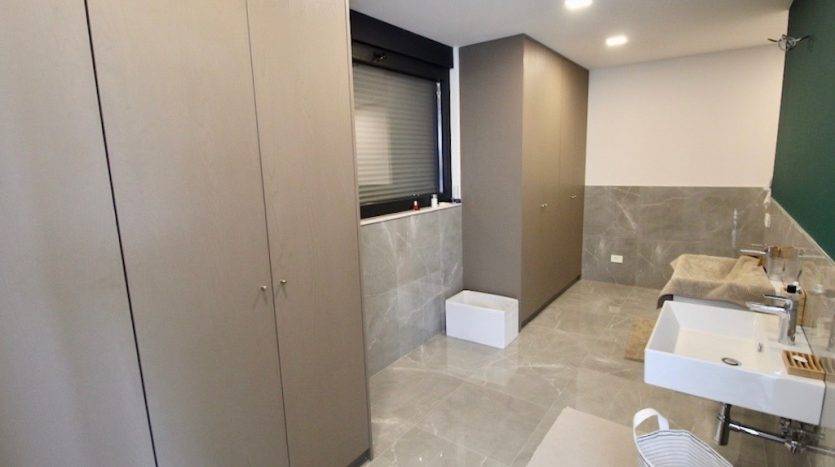 Karadağ, Herceg Novi’deki villada gri dolaplar ve mermer görünümlü fayanslarla modern bir banyo.