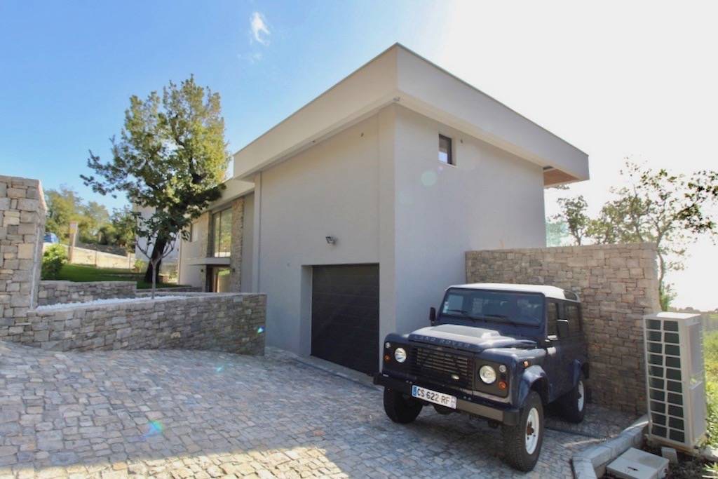 Karadağ, Herceg Novi’de modern villa: taş kaplamalı cephe, garaj ve araçlar için parke döşeli alan.