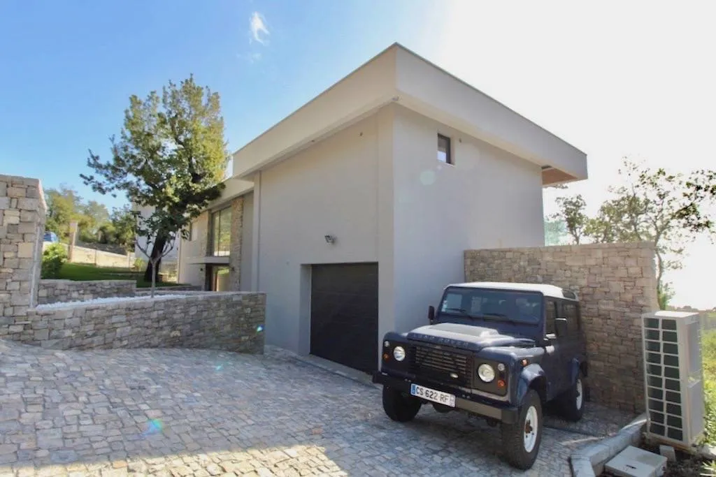 Moderne Villa in Herceg Novi, Montenegro: Fassade mit Steinverkleidung, Garage und gepflasterte Stellfläche für Autos.