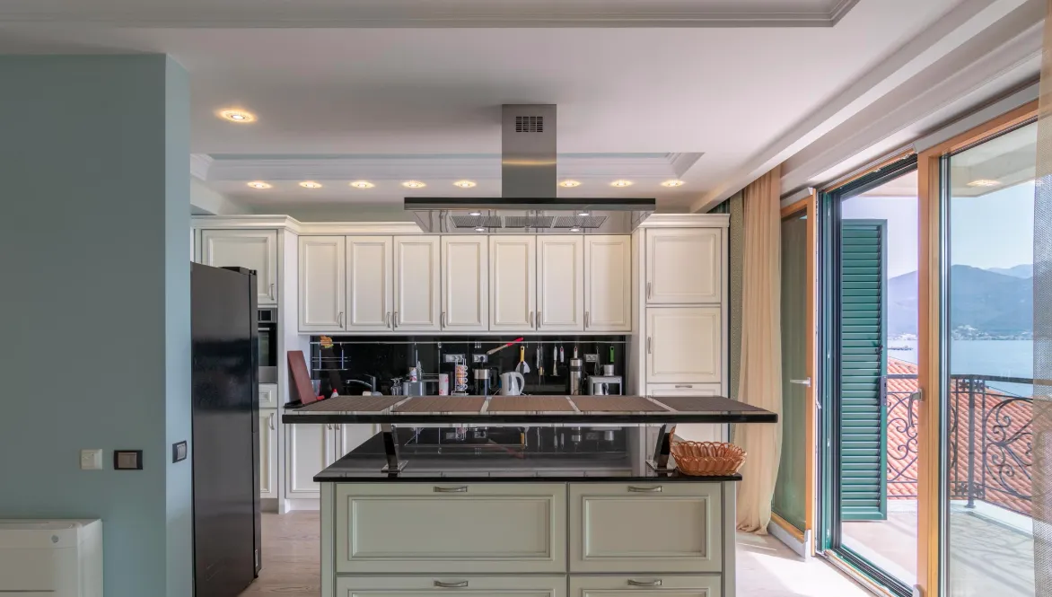 Cuisine moderne avec îlot, électroménager et accès au balcon.
