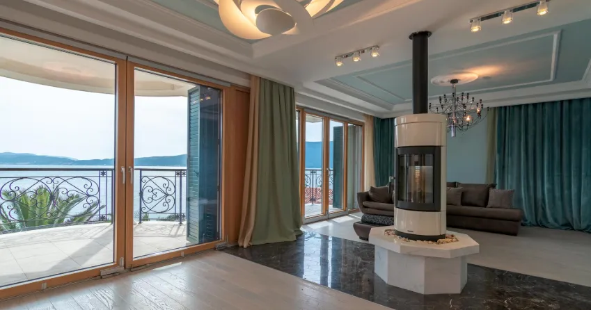 Spacieux salon avec vue sur la mer, cheminée et accès au balcon.