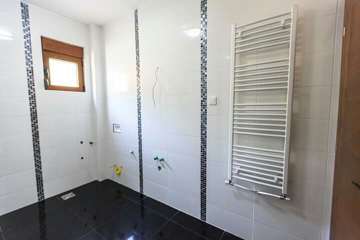 Modernes Badezimmer mit weißen Fliesen und Handtuchheizkörper in einem Haus zum Verkauf in Šušanj, Montenegro.