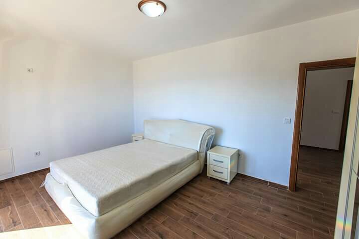 Helles Schlafzimmer in einem Haus in Šušanj, Montenegro: Doppelbett, Nachttische und Fliesenboden in Holzoptik.