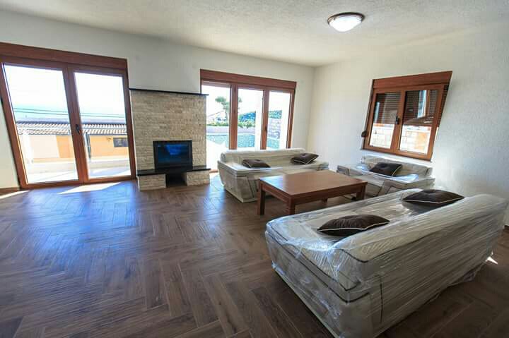 Wohnzimmer in einem Haus in Šušanj, Montenegro: heller Raum mit Kamin, neuen Möbeln und Panoramafenstern mit Meerblick.