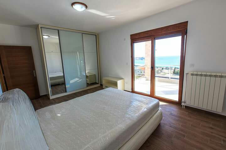 Schlafzimmer mit Meerblick in einem Haus in Šušanj, Montenegro: Doppelbett, Spiegel-Schiebetürenschrank und Zugang zur Terrasse.