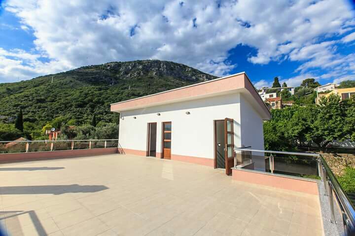 Geräumige offene Terrasse des Hauses in Šušanj, Montenegro, mit Blick auf die Berge und moderner Glas- und Stahlgeländer.