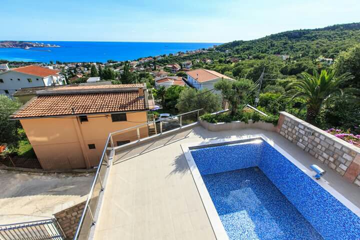 Offener Pool mit Blick auf das Meer und die Berge am Haus in Shushan, Montenegro, mit Terrasse und Glasgeländer.