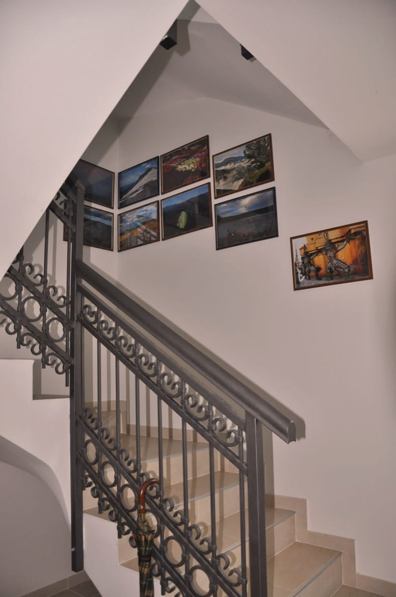 Staircase with wrought-iron railings and paintings on the wall in the interior of a villa in Đenovići, Montenegro.