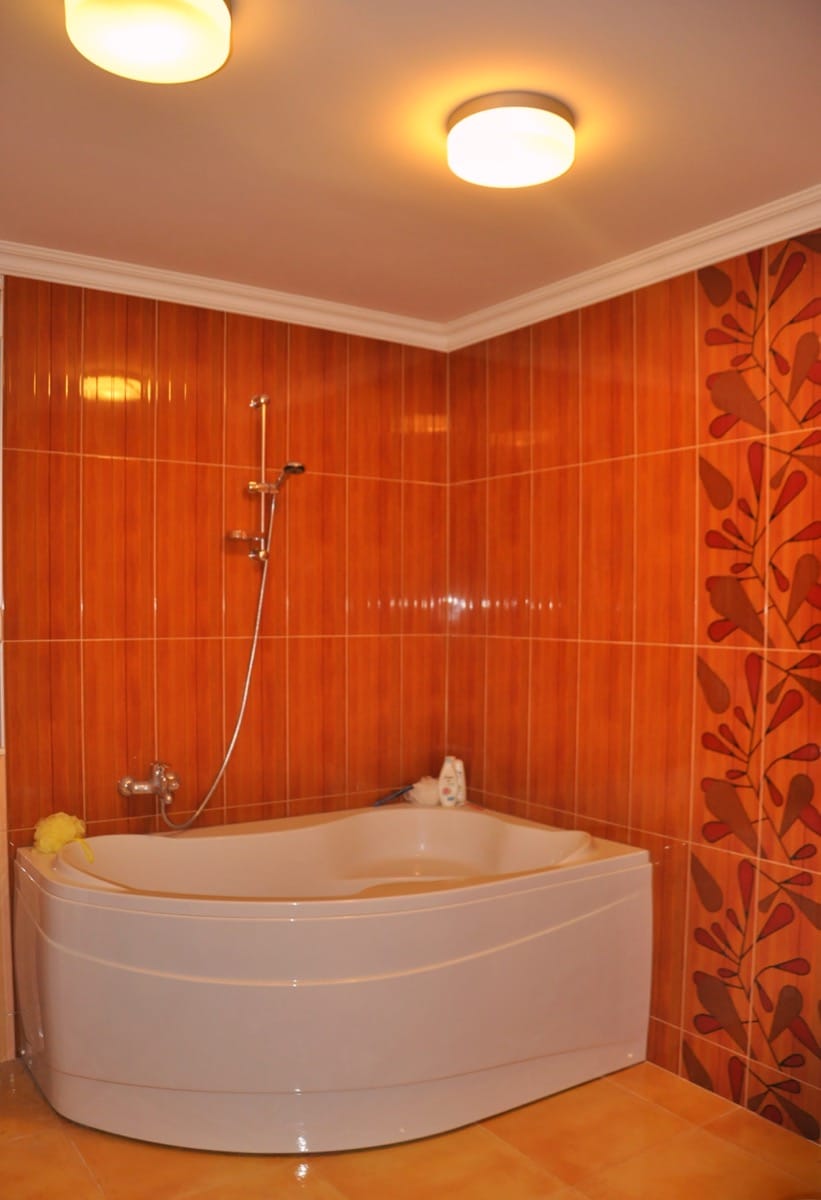 Bathroom with a corner bathtub and orange tiles in the interior of a villa in Đenovići, Montenegro.