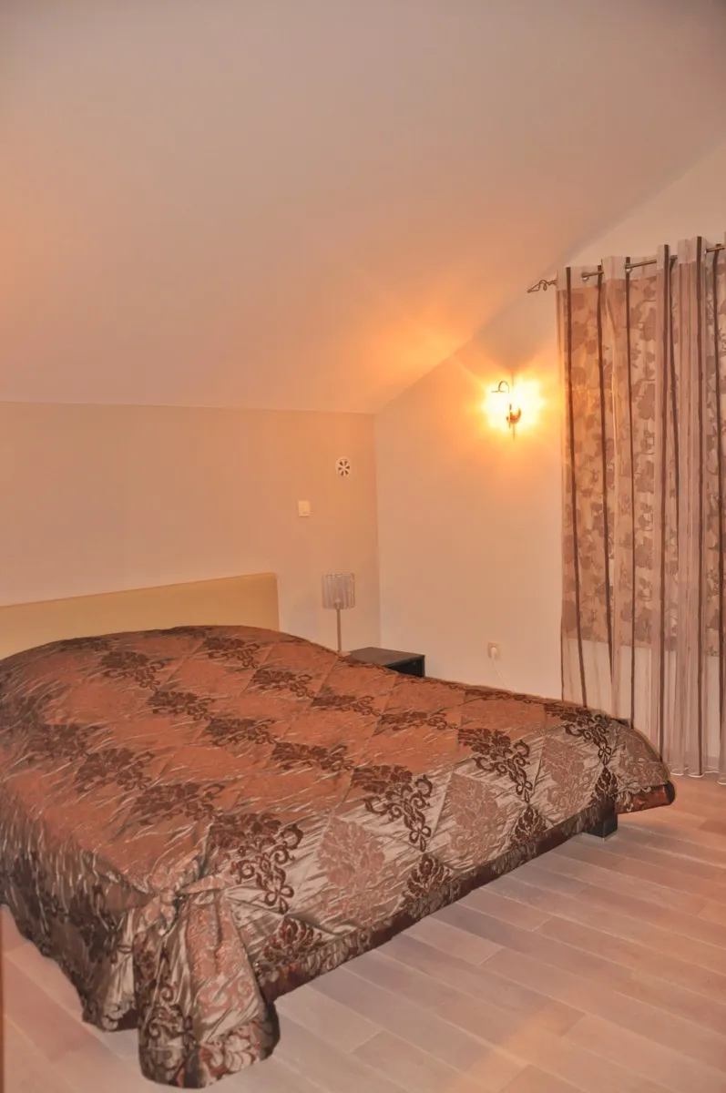 Chambre confortable avec plafond mansardé, lit double et rideaux à motifs.