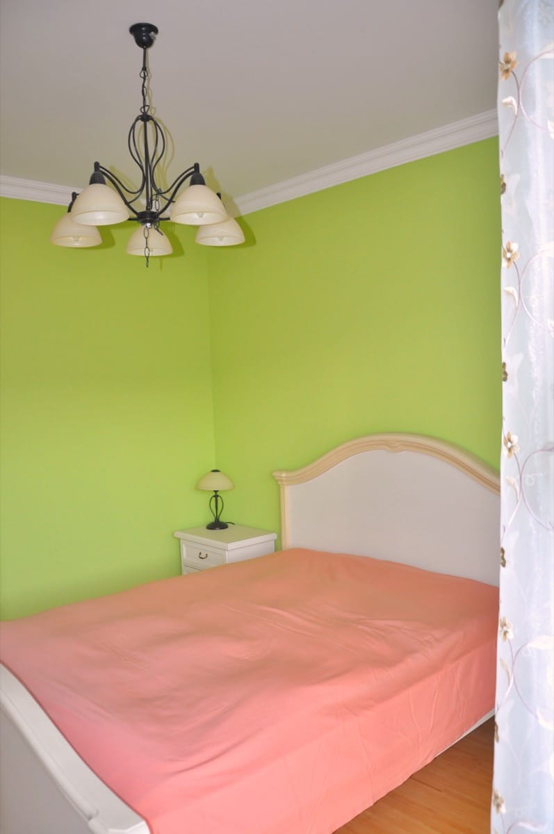 Bedroom with a double bed and green wall accents in a villa in Đenovići, Montenegro. Cozy interior with a chandelier.