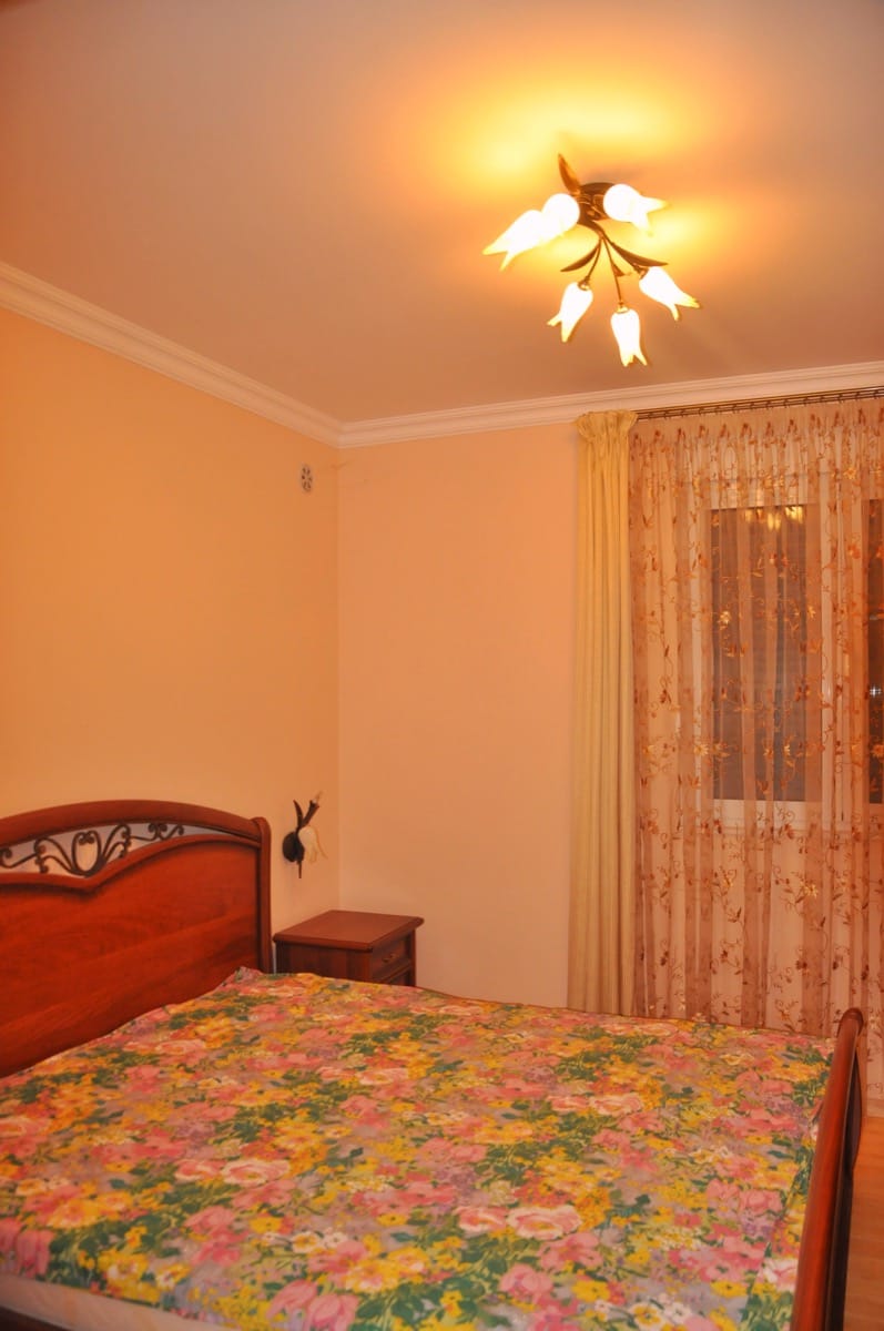 Cozy bedroom with a wooden bed in a villa in Đenovići, Montenegro: classic interior and warm lamp light.