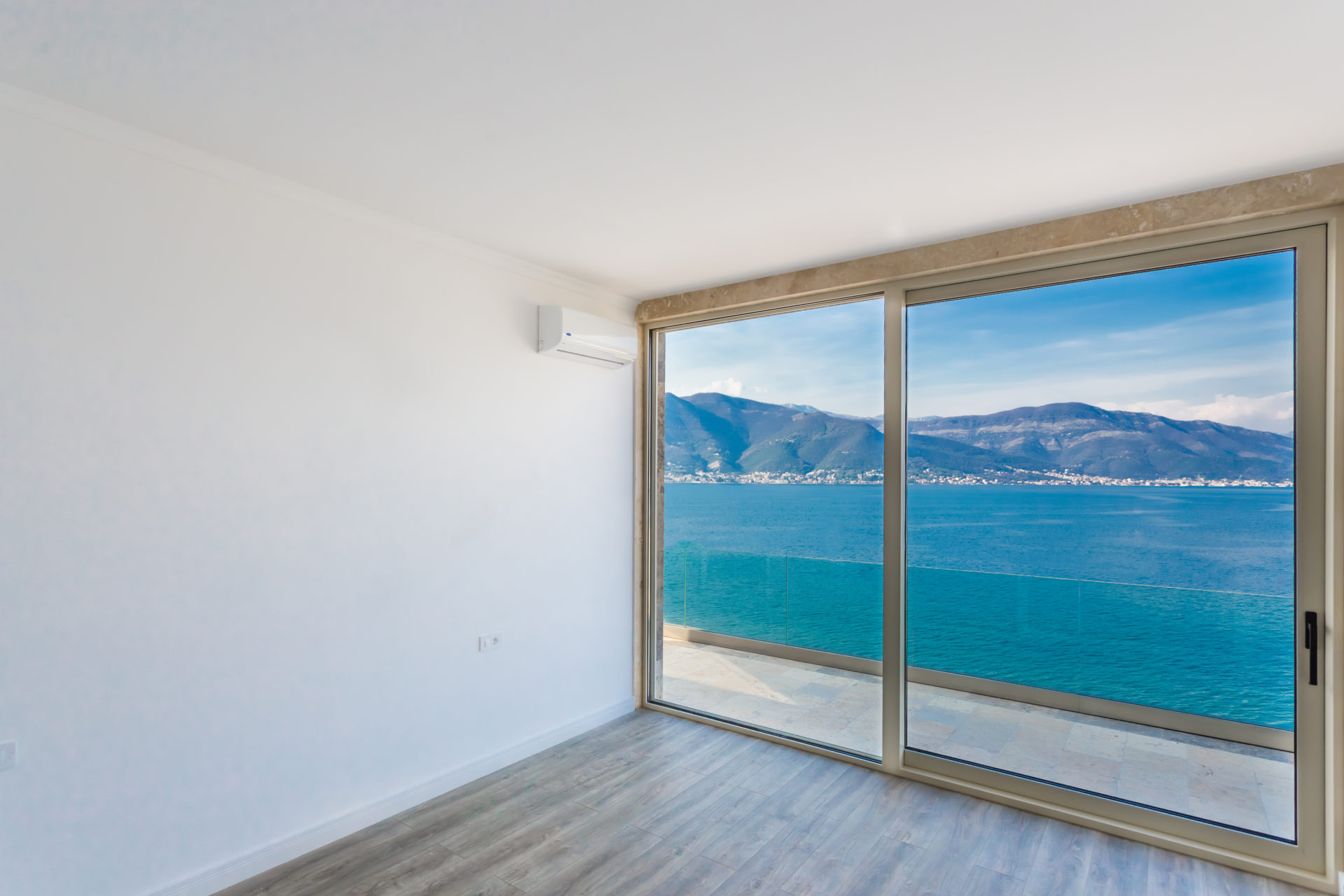 Empty room with panoramic window showing sea and mountains